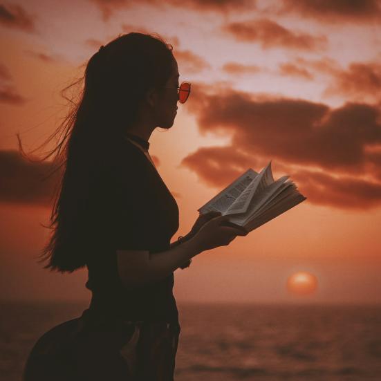 Kvinde med bog i solnedgang. Foto: Unsplash / Aziz Acharki